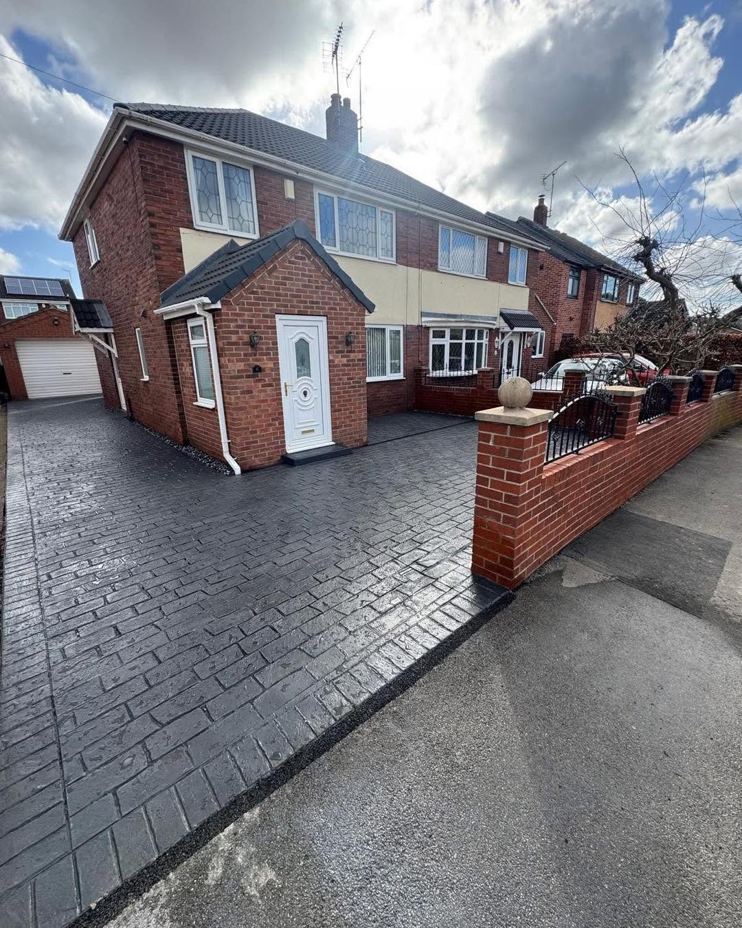 Charcoal ashlar imprinted concrete driveway with brick wall & railings