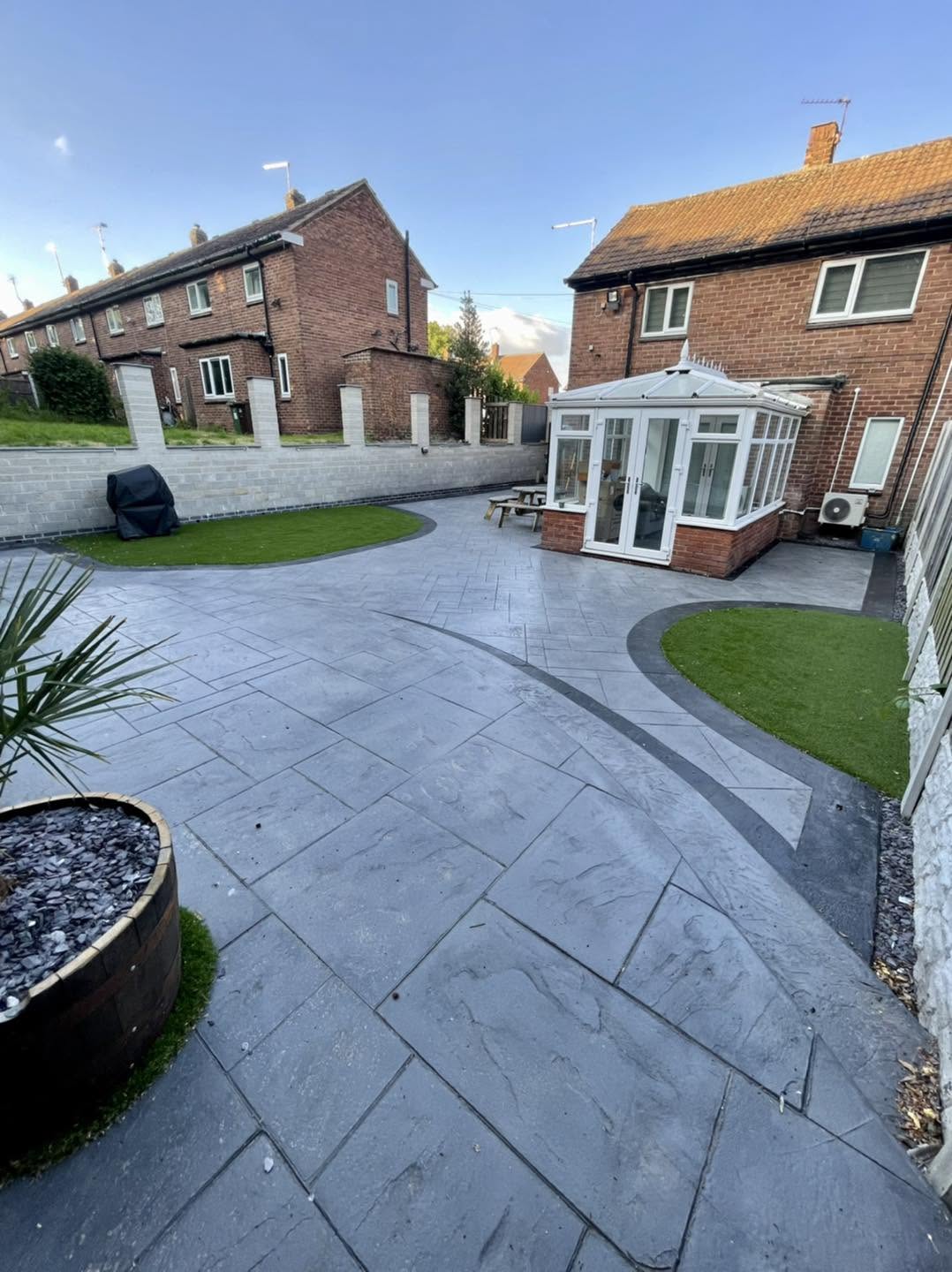 Grey imprinted concrete patio with artificial grass borders