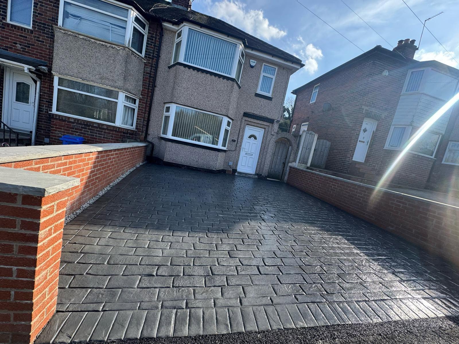 Charcoal imprinted concrete driveway with brick wall